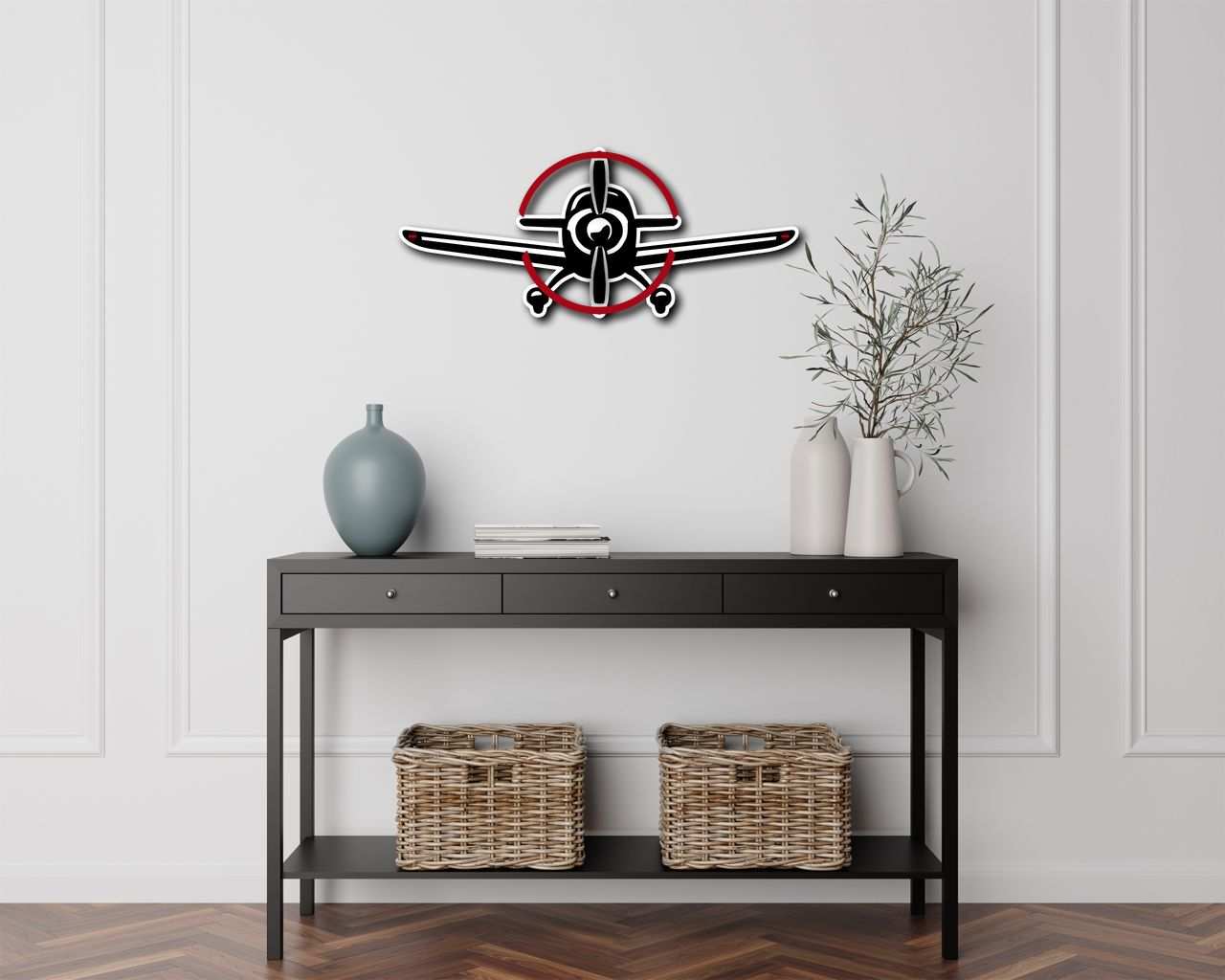 Multicolor metal sign shaped like a propeller plane hanging on a white wall above a black console table with decorative vases and wicker baskets.