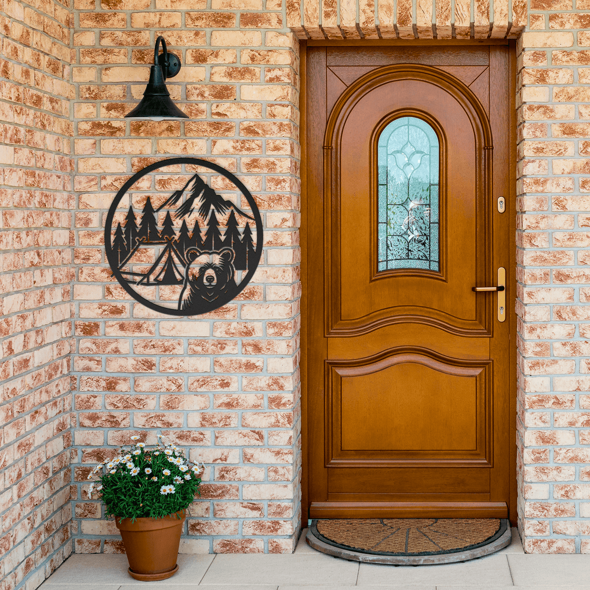 Metal wall art featuring a bear and camping scene mounted on a brick wall beside a wooden door