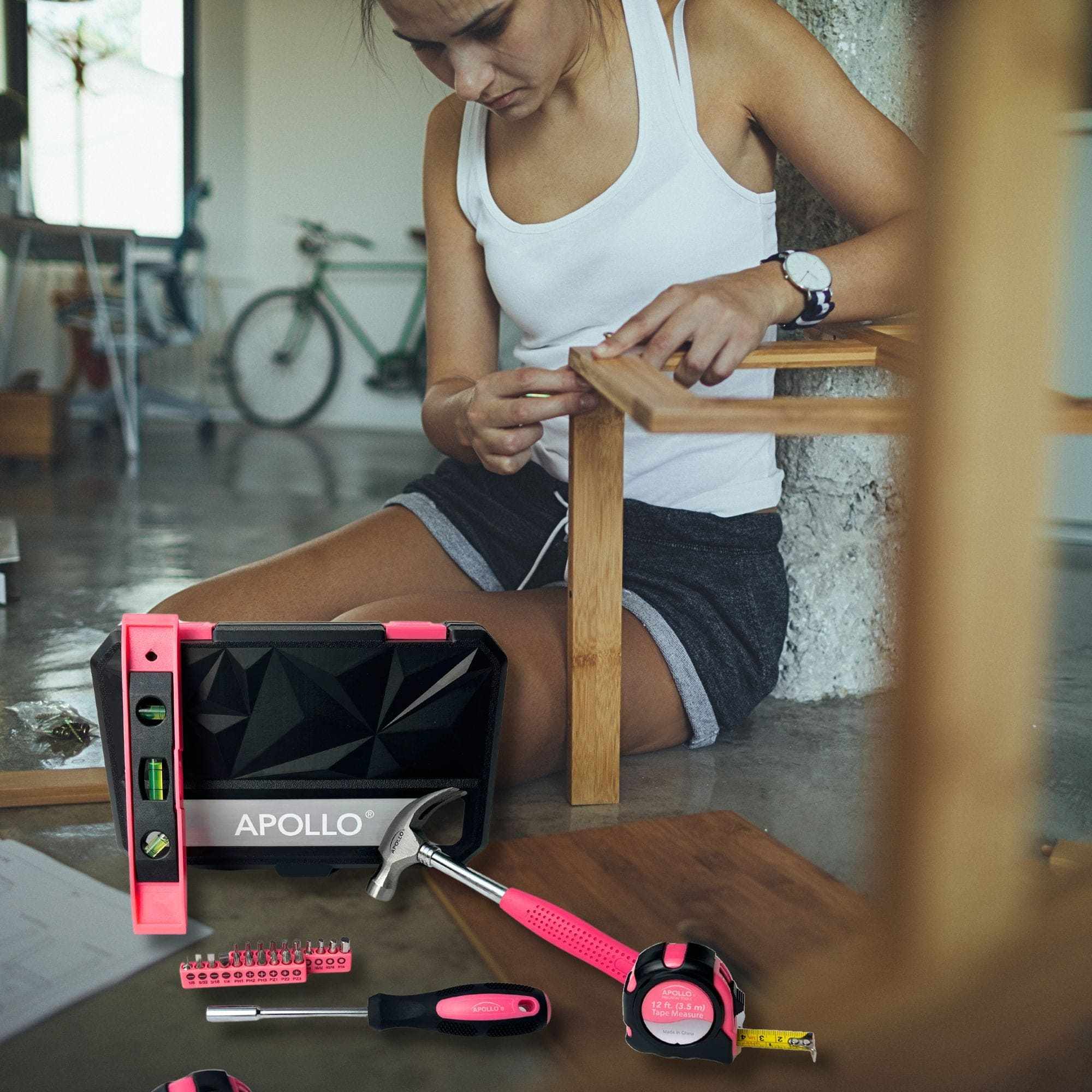 Pink tool set with hammer, tape measure, bit driver, magnetic level, and storage case in use for DIY furniture repair