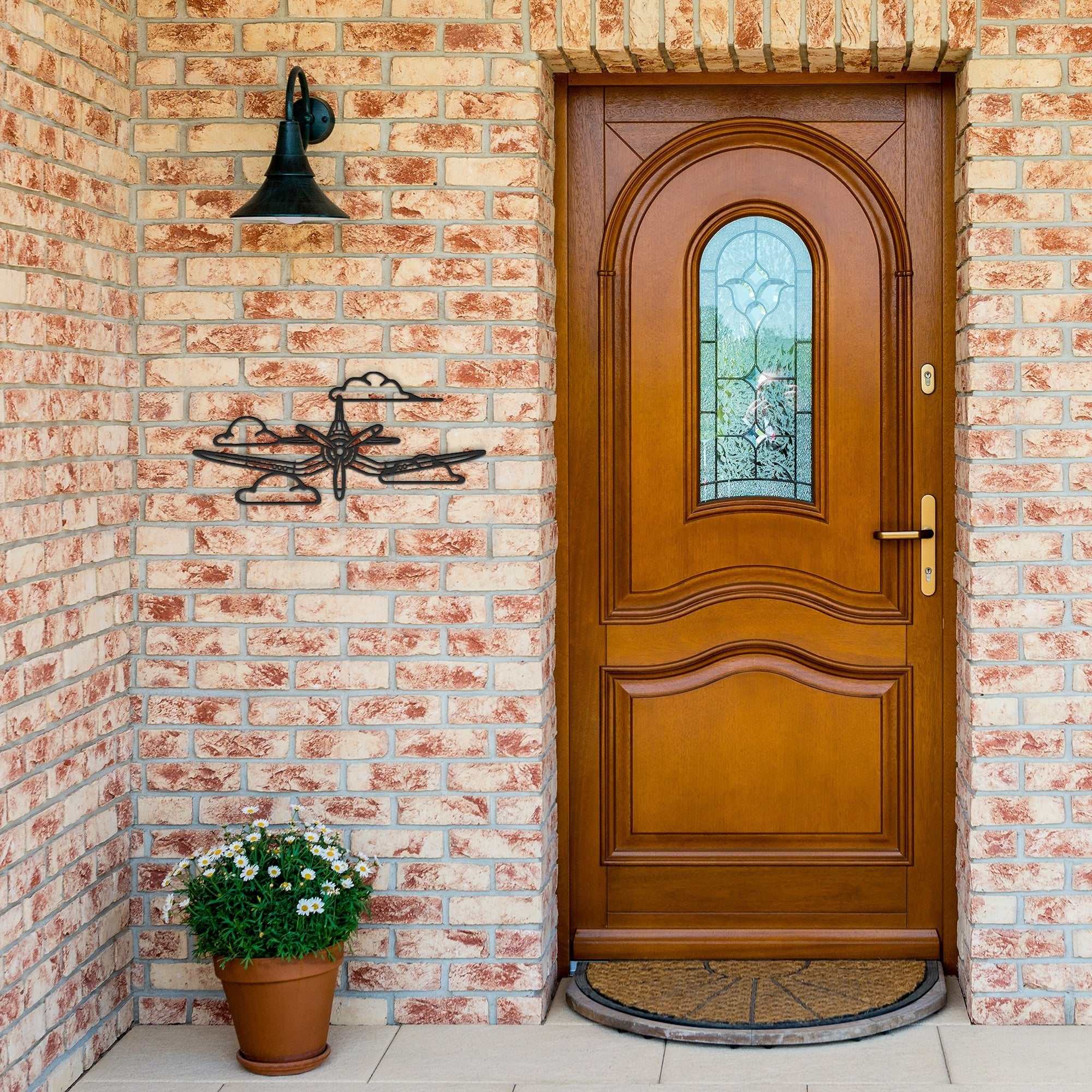 F4U Clouds WWII Corsair metal wall art in black steel mounted on brick exterior near wooden door