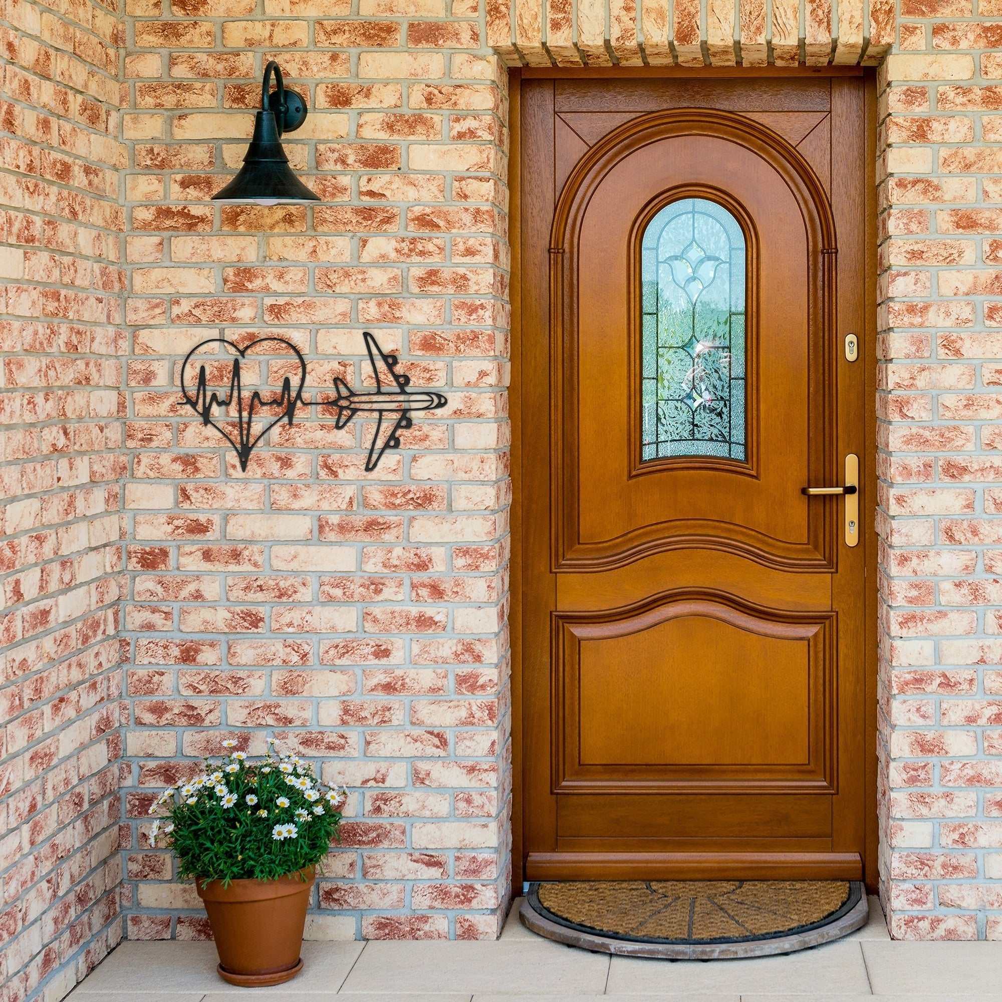 Minimalist metal wall art featuring a heartbeat and airplane design on brick wall by wooden door
