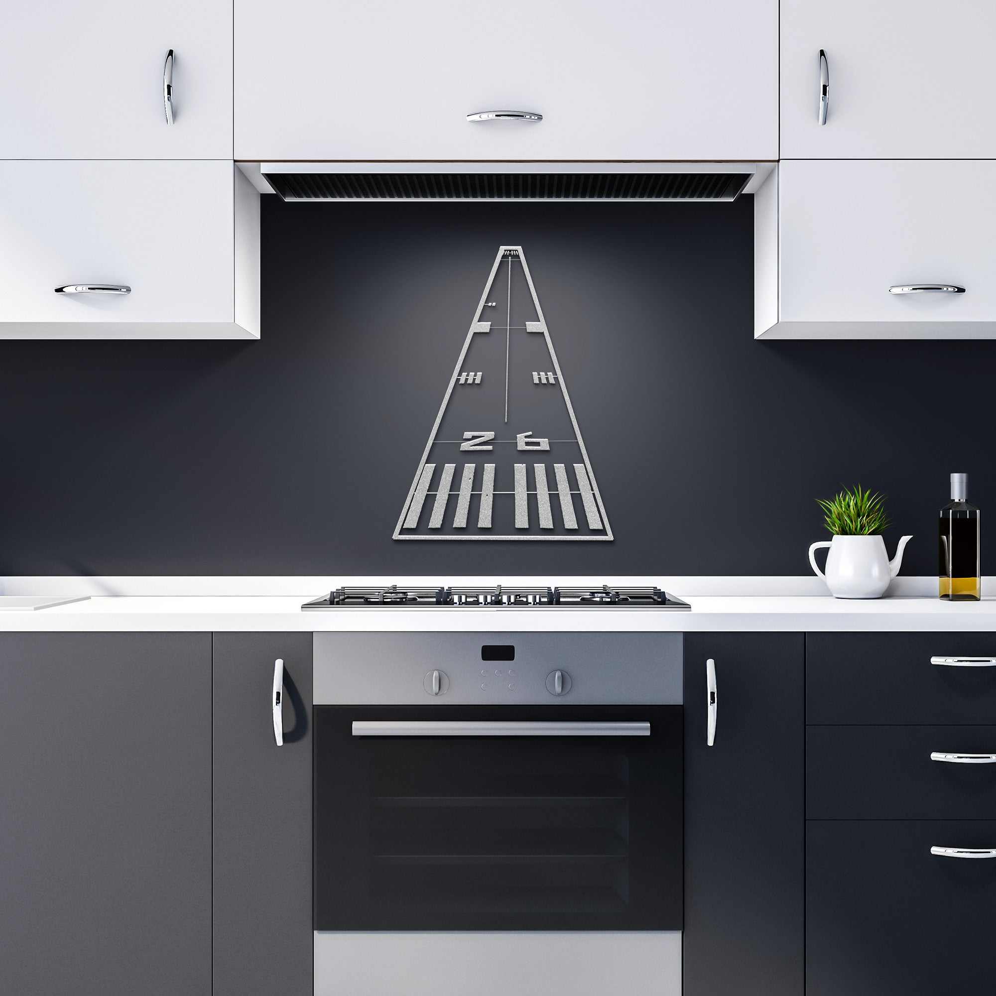 Metal wall art runway airplane sign hanging above a modern kitchen stove with black and white cabinets