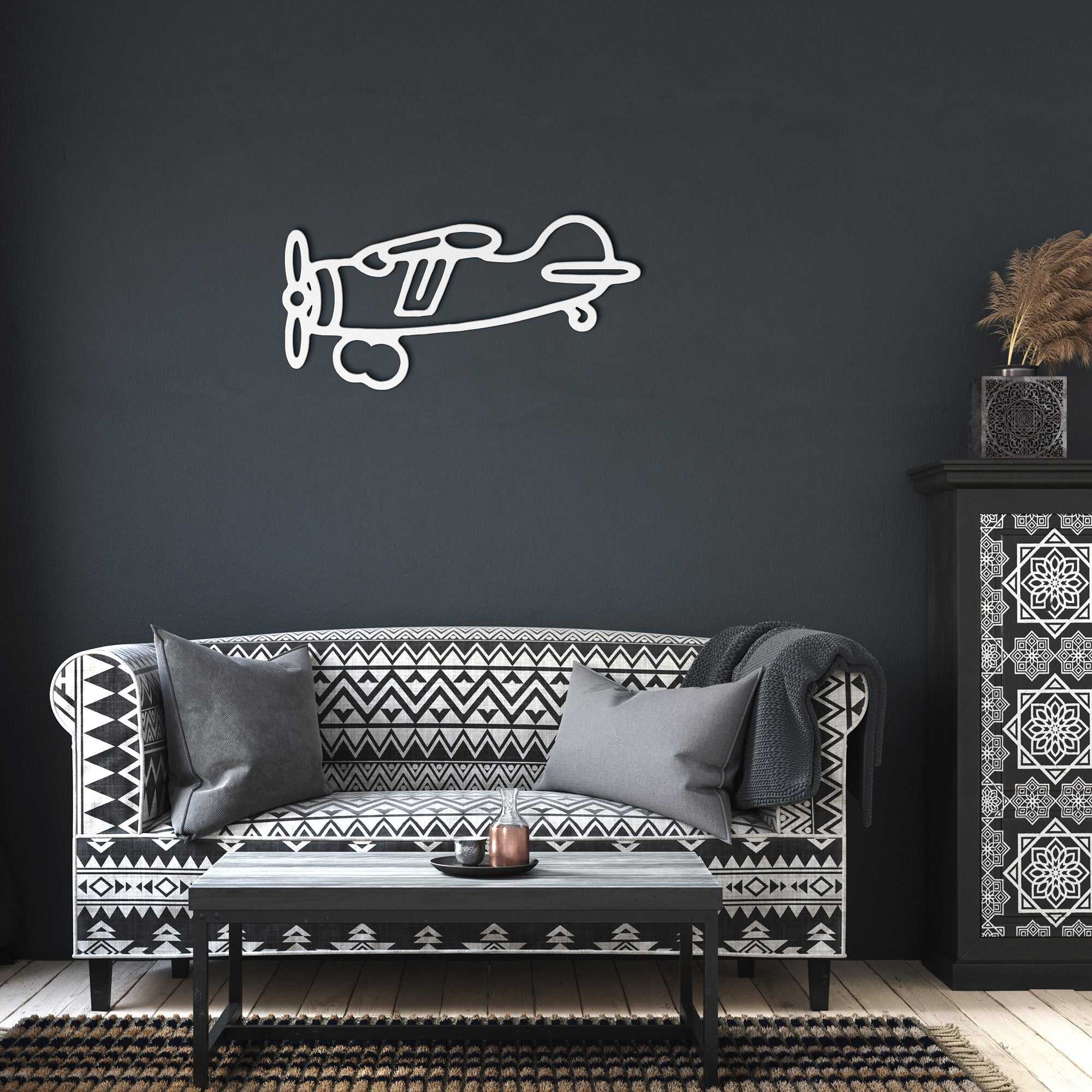 Vintage airplane metal wall art in white hanging above a patterned black and white sofa in a modern industrial living room