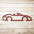 Red powder-coated steel automotive metal wall art featuring a convertible silhouette on a wooden background