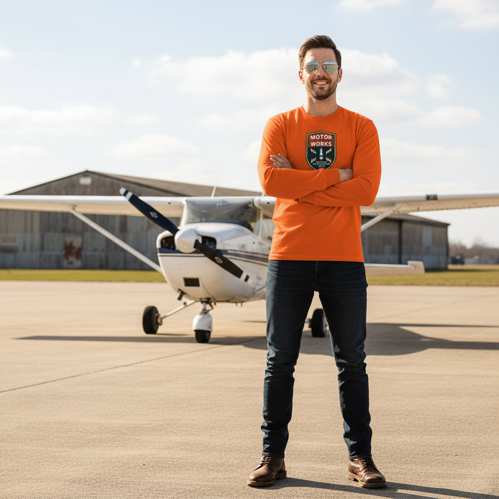 Man wearing orange Motor Works long sleeve T-shirt standing by small airplane on runway