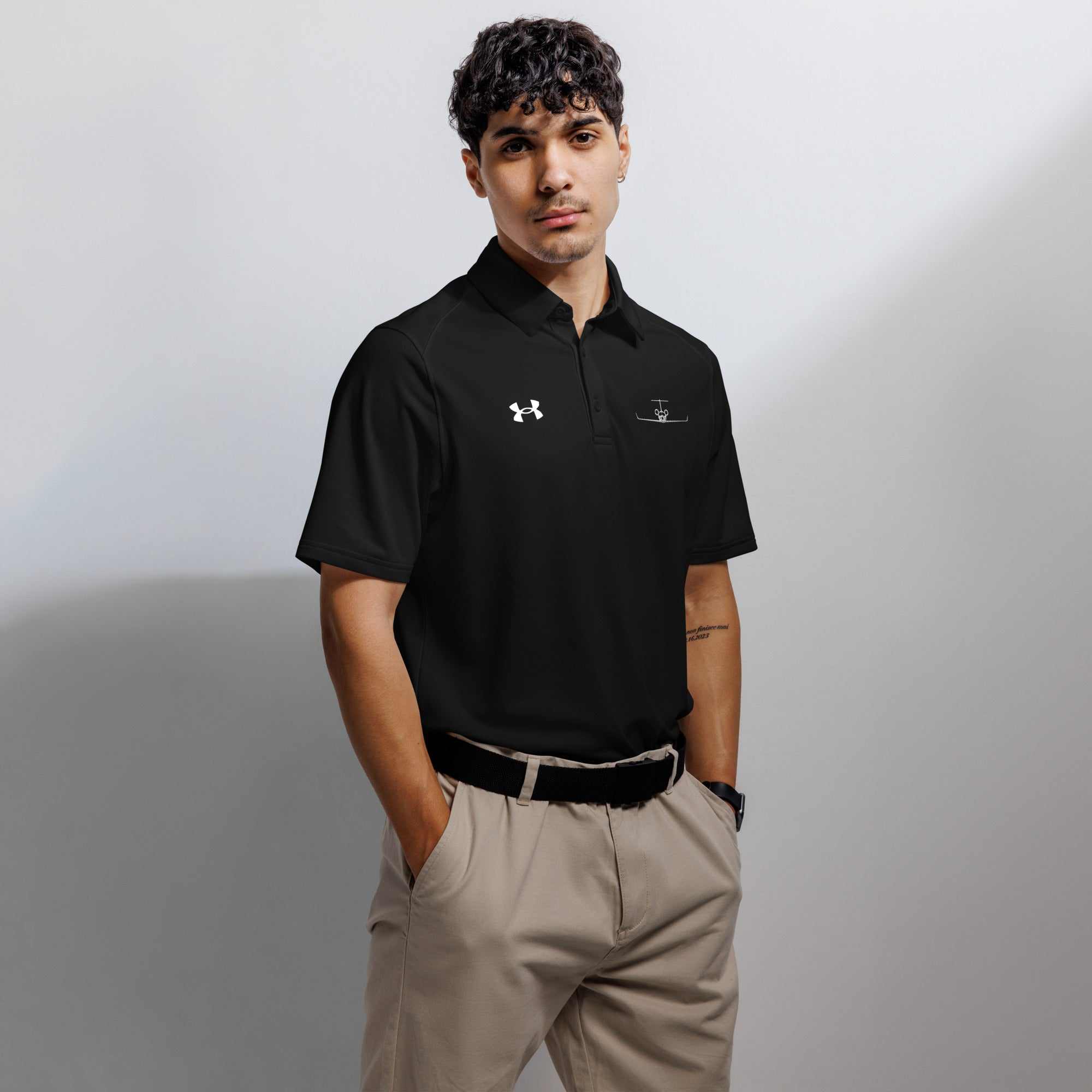 Man wearing black pilot polo shirt with embroidered private jet logo and Under Armour logo