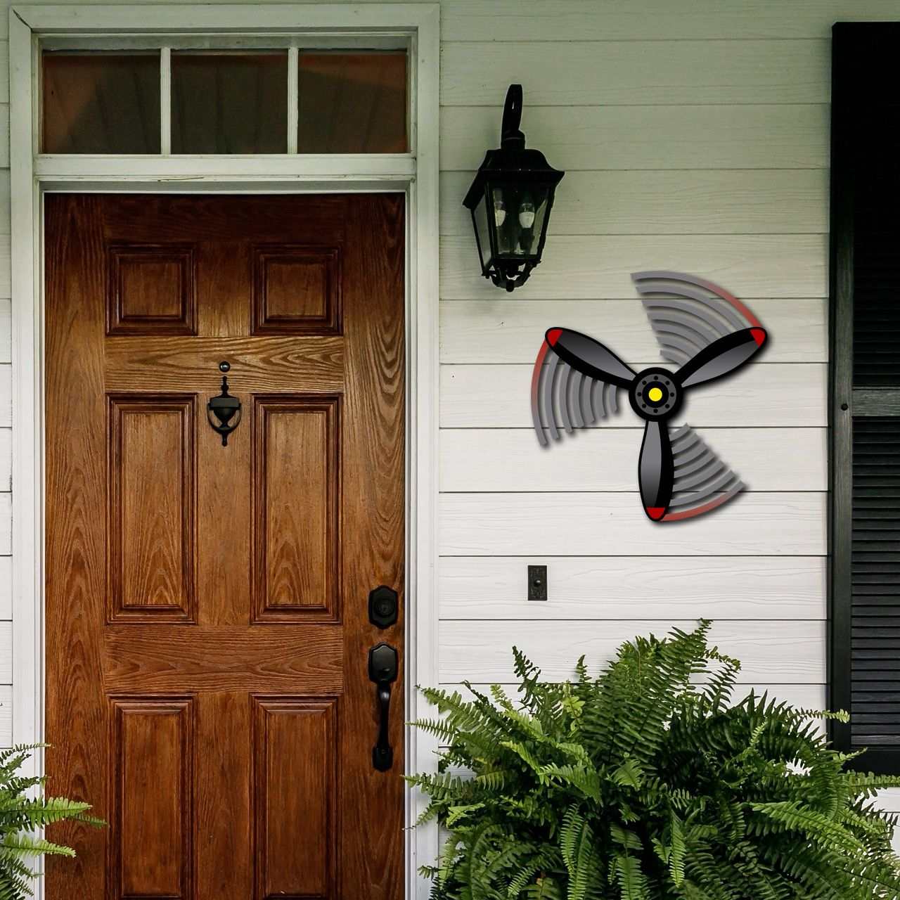 Multicolor metal sign propeller spin wall art hanging on white porch wall near wooden door and green plants