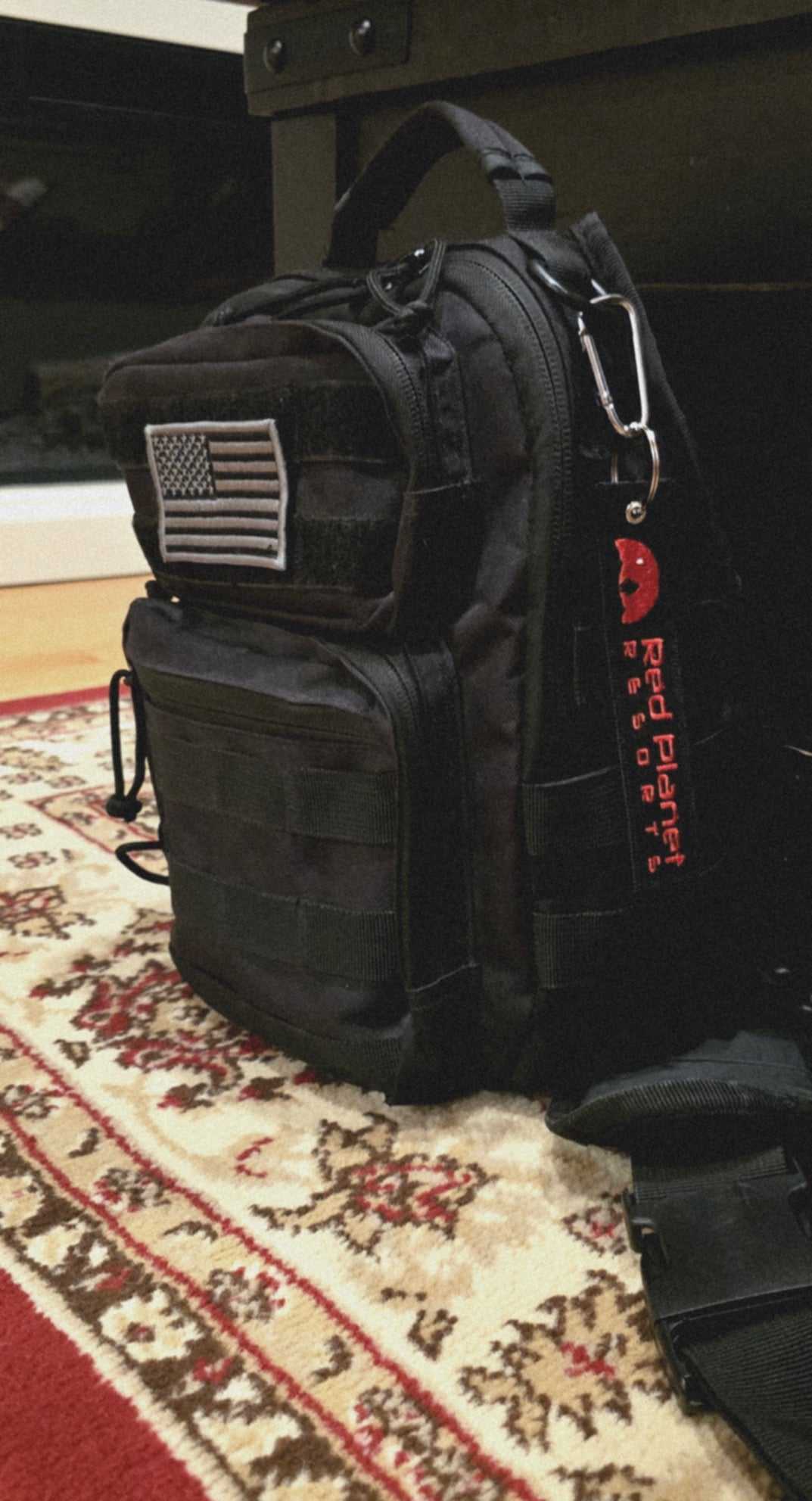 Black tactical bag with American flag patch and red Mars Approved Flight Tag keyring attached