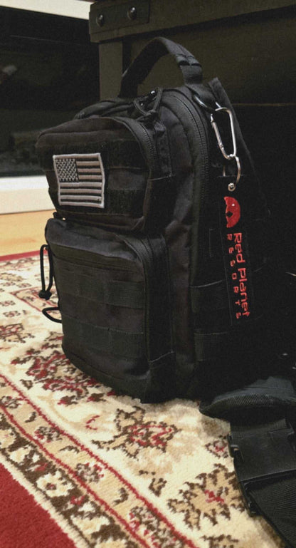 Black tactical bag with American flag patch and red Mars Approved Flight Tag keyring attached