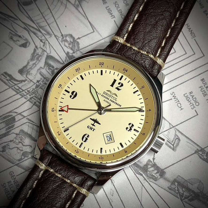 B-17 Flying Fortress tribute watch with polished stainless steel case, beige dial, brown leather strap with stitching, and GMT function