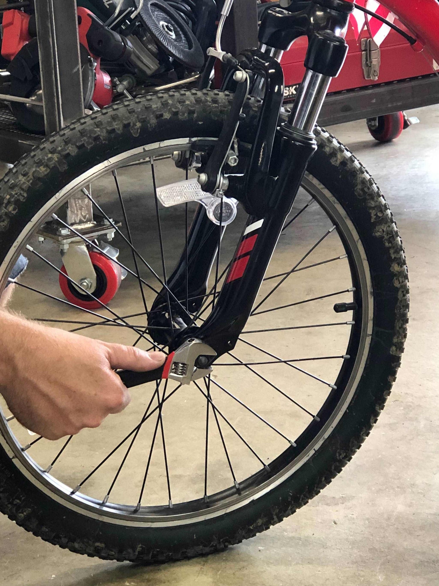 Hand using adjustable wrench from 71 piece household tool kit to fix bicycle wheel bolt