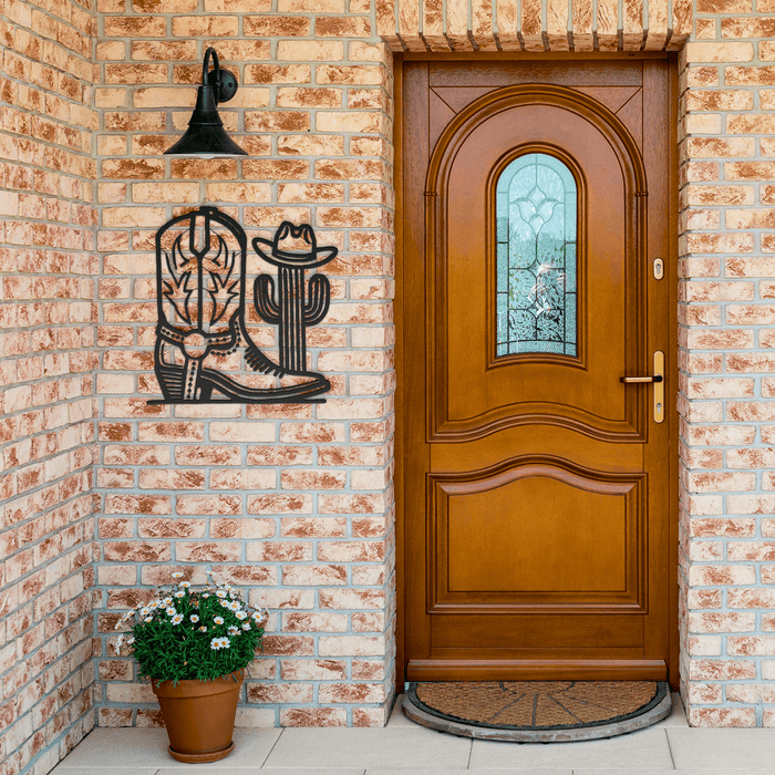 Metal cowboy boot and cactus wall art mounted on brick porch near wooden door
