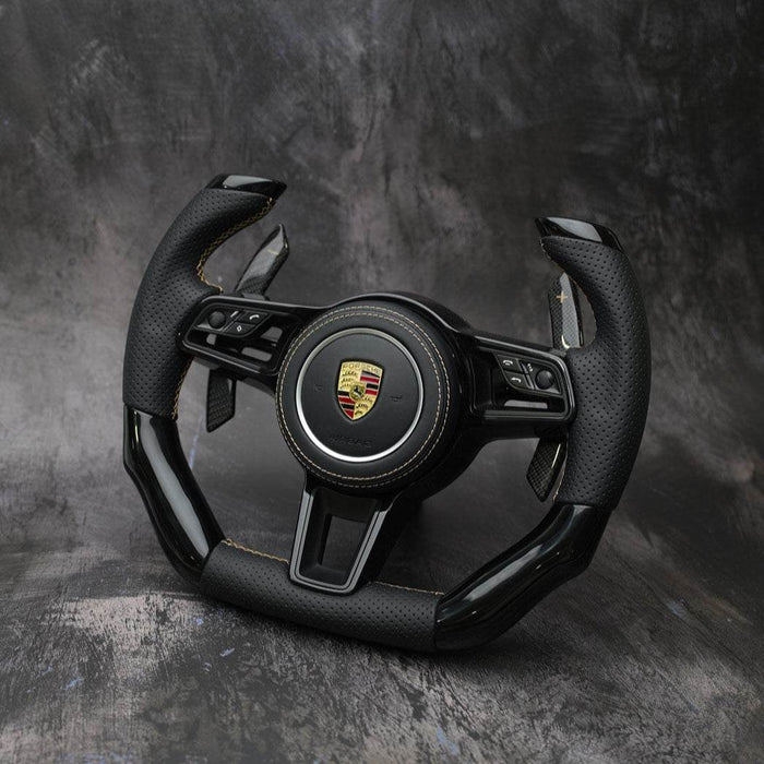 Black steering wheel with Porsche logo on a dark gray background