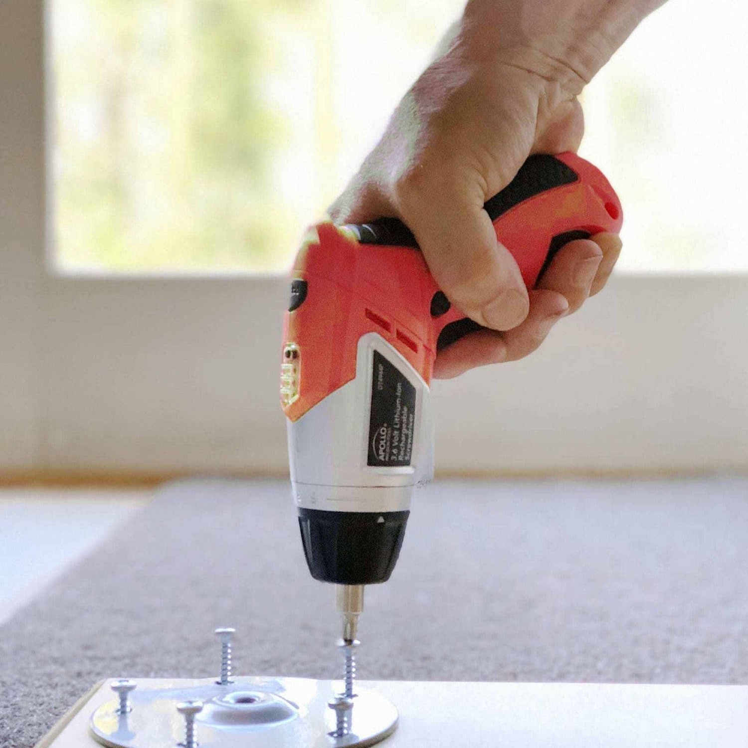 3.6 Volt Lithium-Ion Rechargeable Cordless Screwdriver in use fastening screws on a surface with a red and black ergonomic handle
