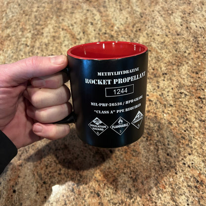 Rocket propellant coffee mug shaped like a NASA fuel drum with hazard markings and red interior