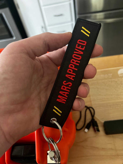 Mars Approved Flight Tag embroidered keyring with red lettering and metal grommet