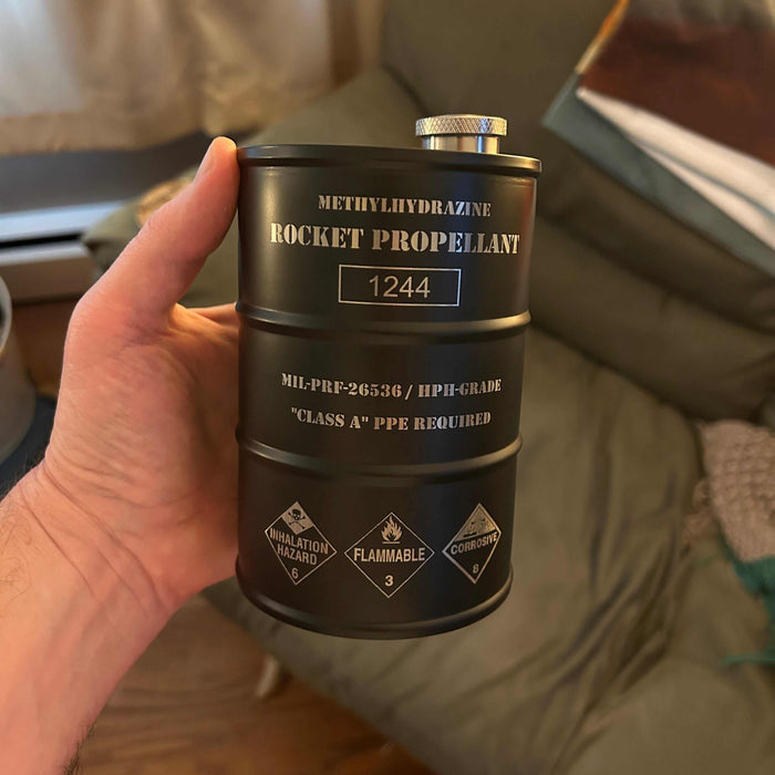 Rocket propellant flask shaped like NASA hydrazine fuel barrel with hazard markings and stainless steel finish