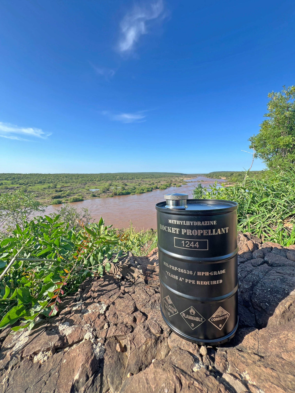 Rocket propellant flask shaped like NASA hydrazine fuel barrel with hazard markings and stainless steel finish