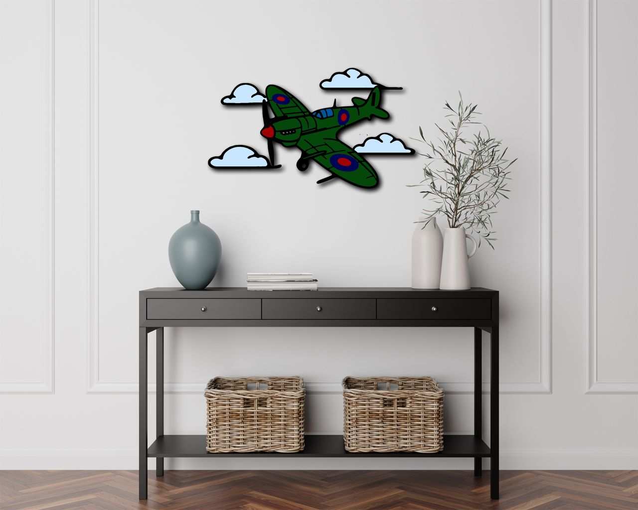 Multicolor metal sign featuring a green Spitfire plane with clouds, wall-mounted above a modern black console table with decorative vases and wicker baskets.