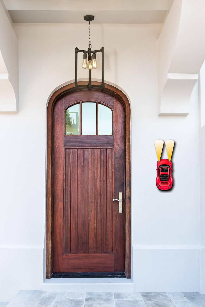 metal car wall art with red finish and bold headlights mounted beside wooden front door in modern entryway