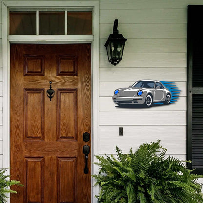 Garage wall decor steel art featuring a multicolor performance coupe silhouette mounted on white outdoor wall next to wooden door