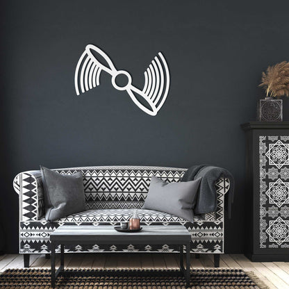 White propeller metal wall art mounted on dark gray wall above black and white patterned sofa in modern living room