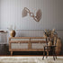Copper propeller metal wall art mounted on a gray paneled wall above wooden furniture in a rustic living space