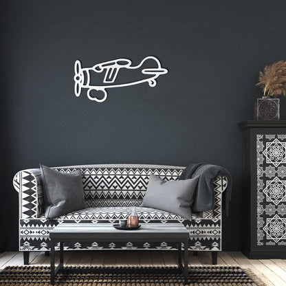 Vintage airplane metal wall art in white hanging above a patterned black and white sofa in a modern industrial living room