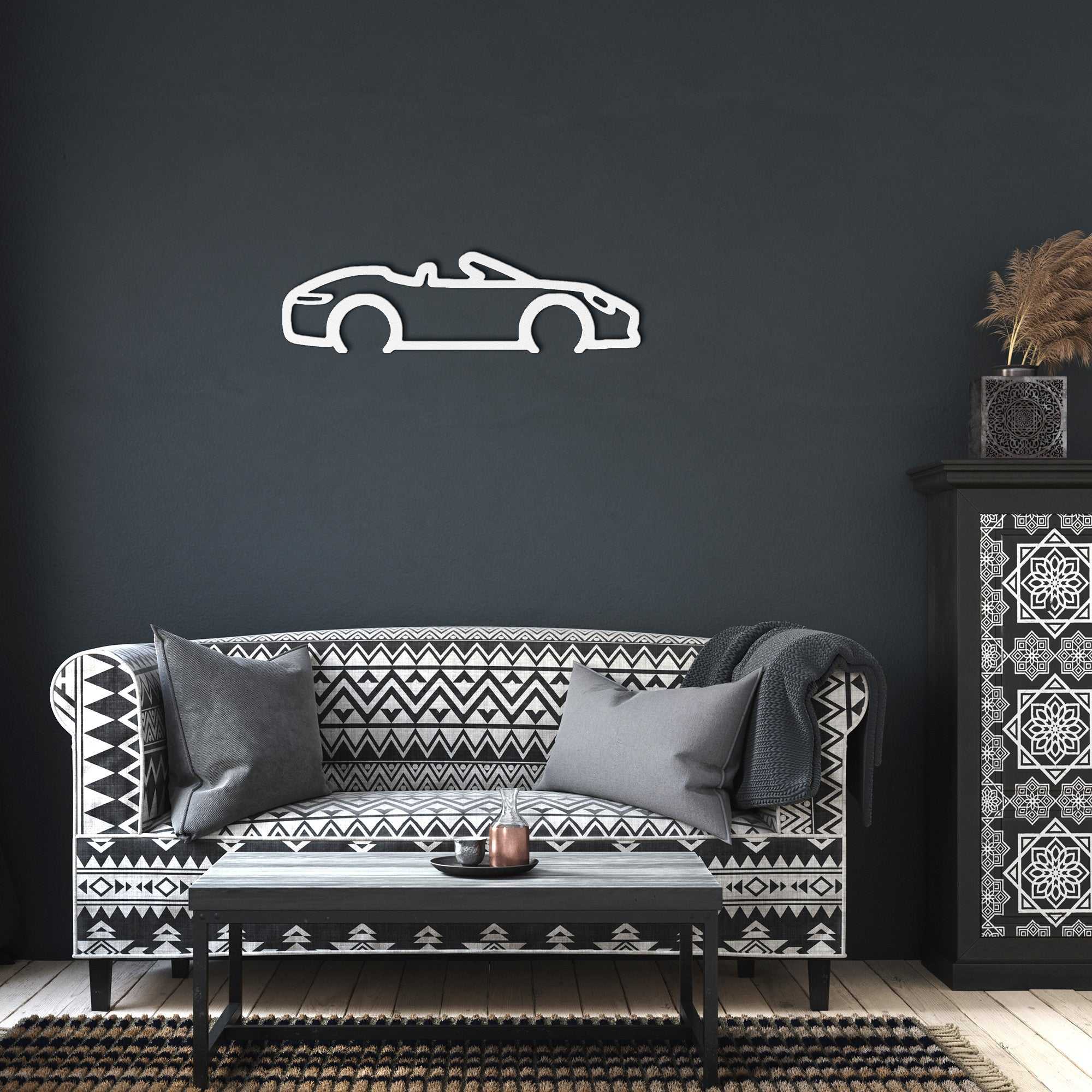 Automotive metal wall art convertible silhouette in powder-coated steel displayed on dark wall above patterned sofa in modern living room