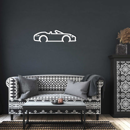 Automotive metal wall art convertible silhouette in powder-coated steel displayed on dark wall above patterned sofa in modern living room