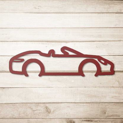 Red powder-coated steel automotive metal wall art featuring a convertible silhouette on a wooden background