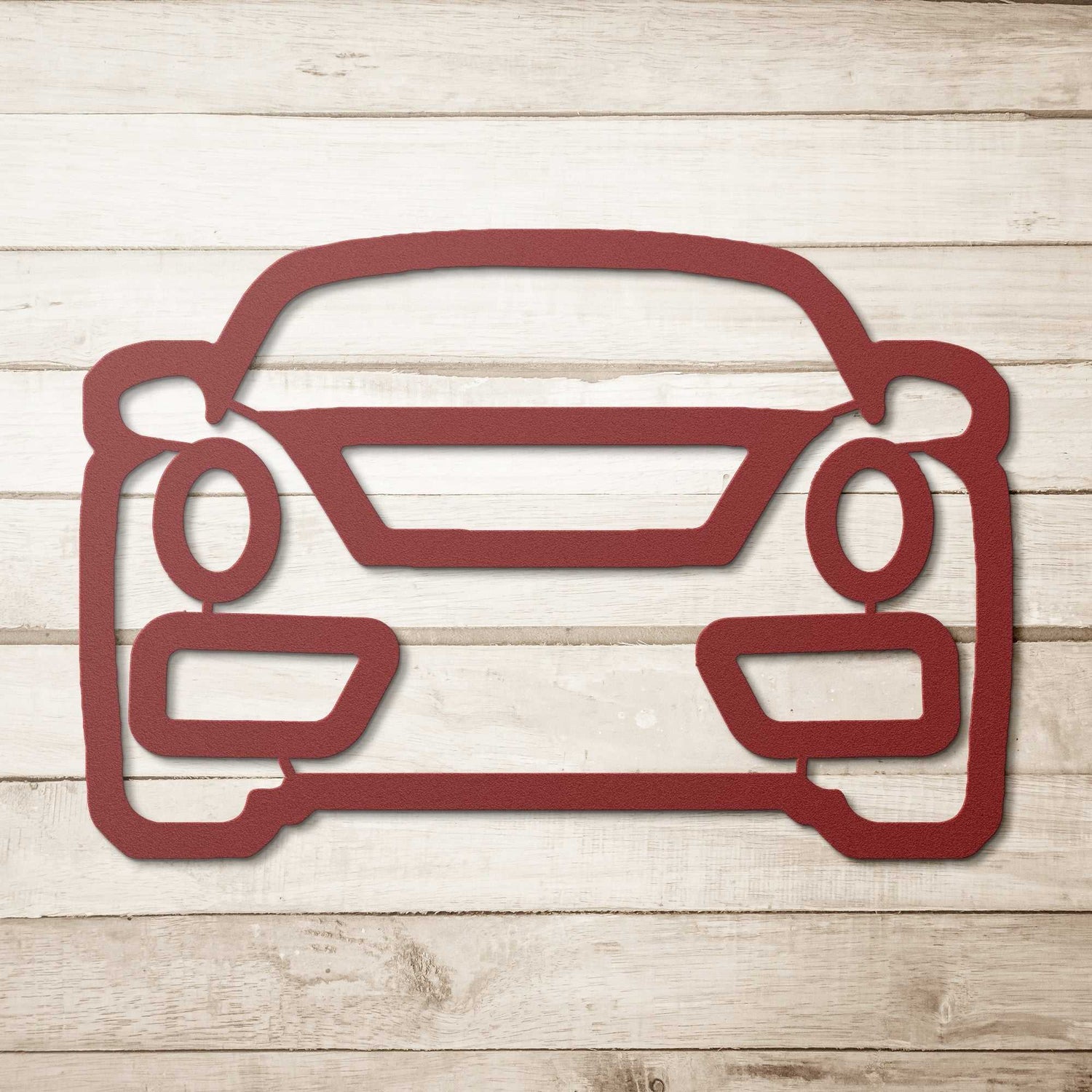 Red metal wall art shaped like a car front on wooden background