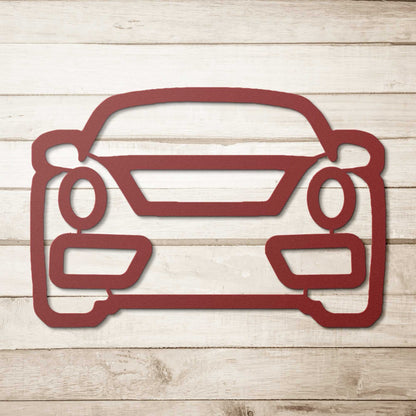Red metal wall art shaped like a car front on wooden background