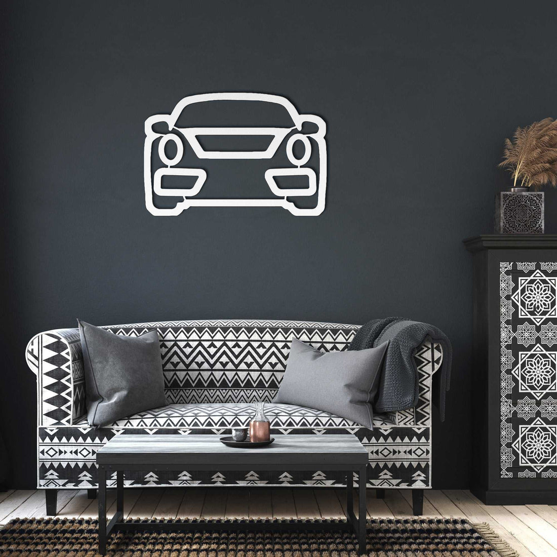 Minimalist metal wall art car outline mounted on dark living room wall above patterned black and white sofa