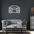 Minimalist metal wall art car outline mounted on dark living room wall above patterned black and white sofa