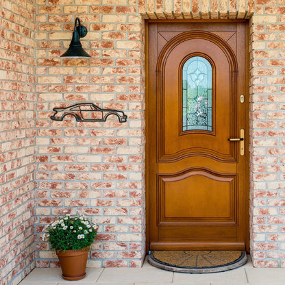 Metal wall art car silhouette mounted on brick wall near wooden door