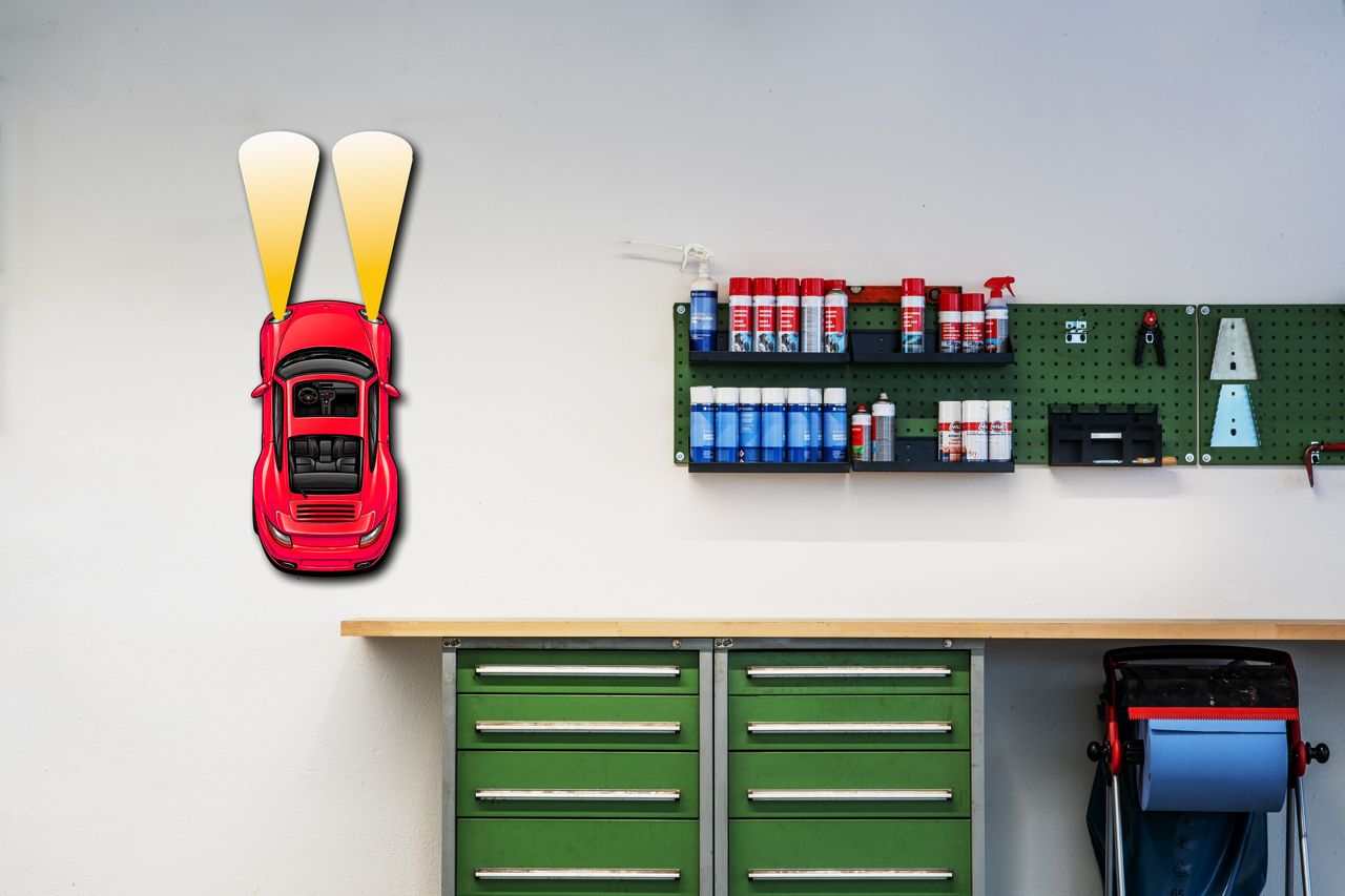 metal car wall art with red headlights mounted in a garage workshop setting