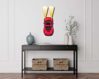 Red metal car wall art with illuminated headlights mounted above black console table in modern room