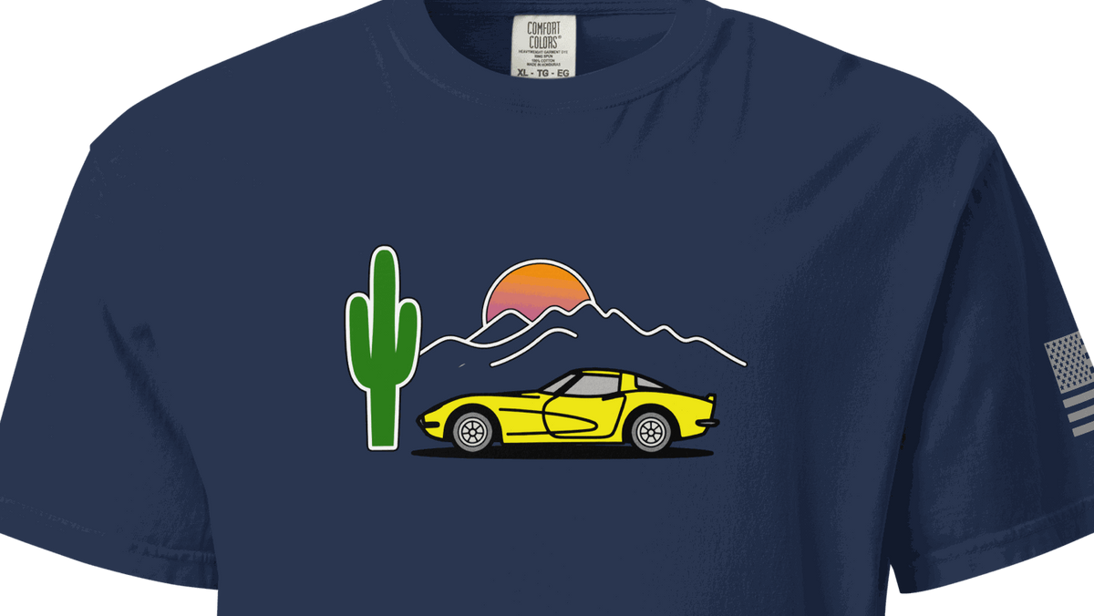 Navy blue t-shirt with a graphic of a yellow car, cactus, and sunset on a black background